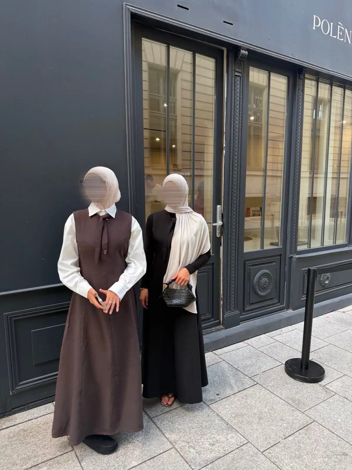 Deux femmes en robe chasuble longue, chocolat et noire, devant une devanture sombre